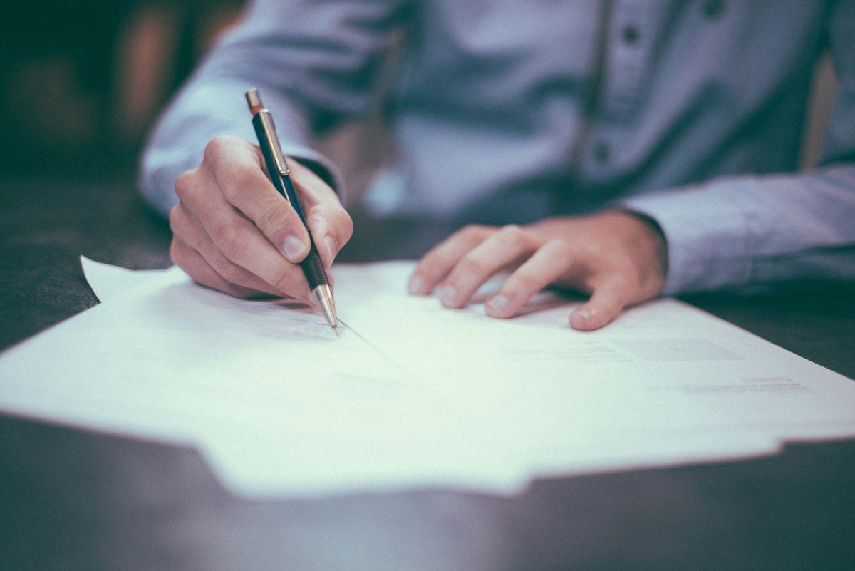 A person reviewing and signing paperwork at a desk