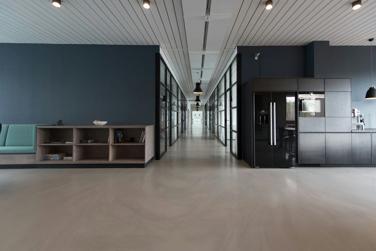 A modern office corridor lined with floor-to-ceiling glass