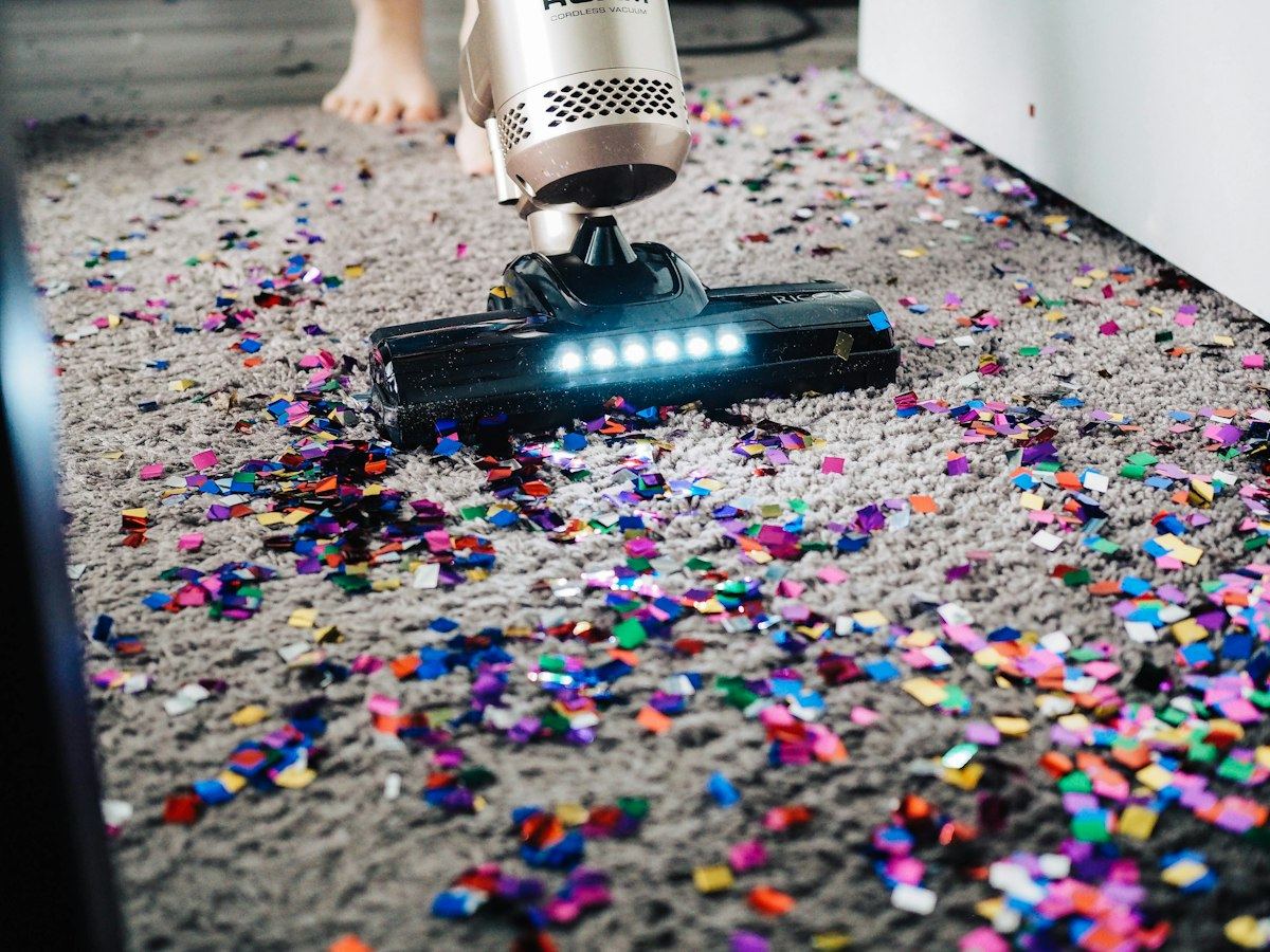 A vacuum clearing fine debris from a carpeted floor