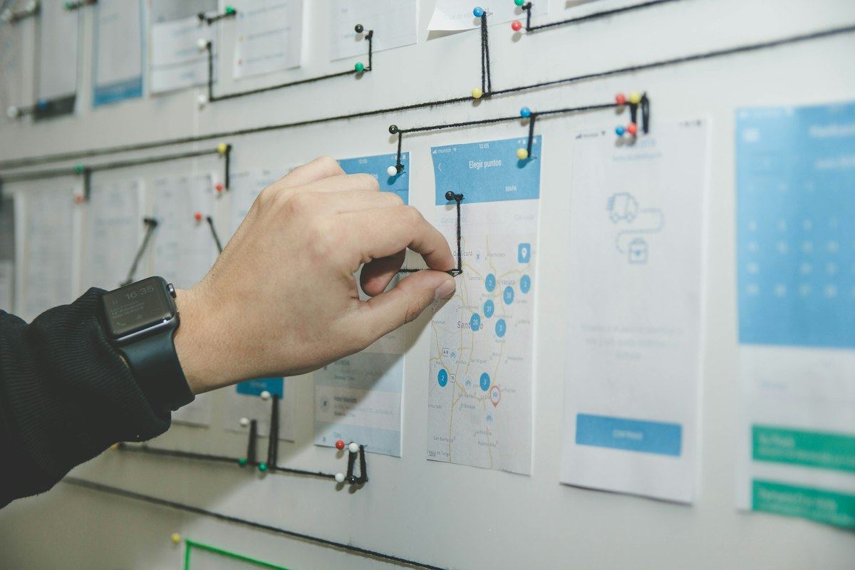 A hand pinning up plans on a planning board