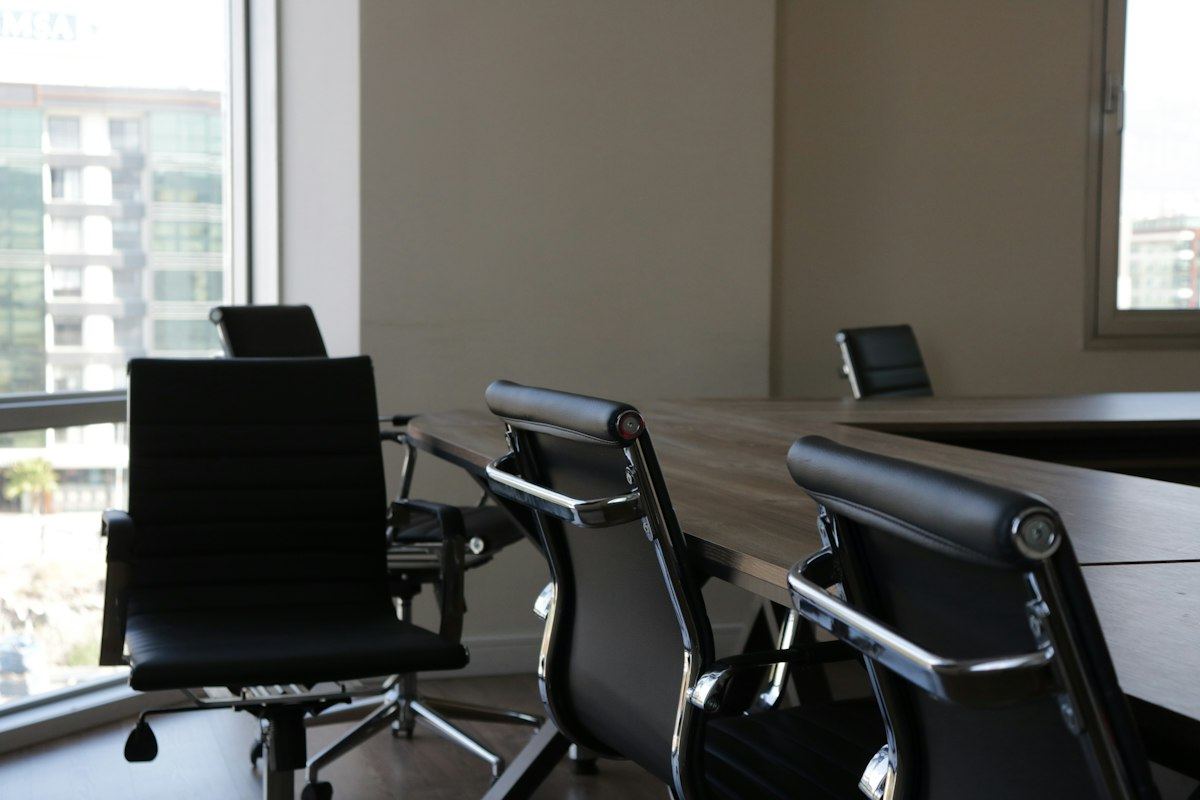 A quiet meeting room with black chairs beside a window