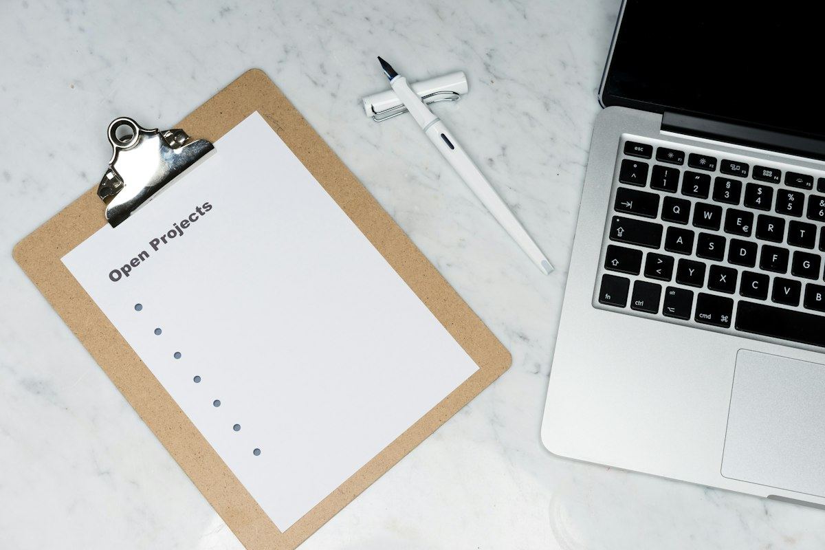 A clipboard with a checklist beside a laptop