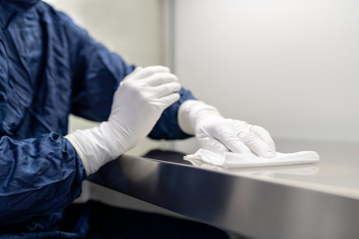 A gloved hand wiping a metal surface