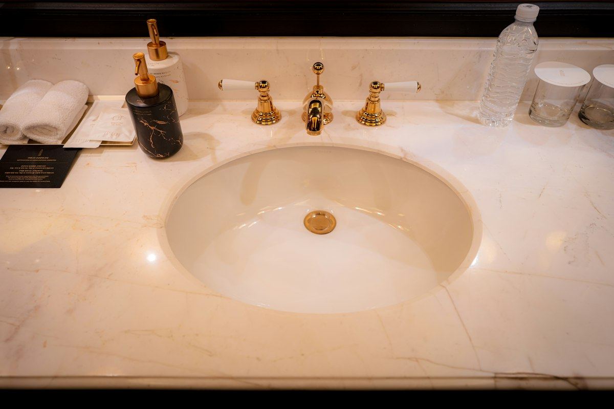 A marble washroom basin with gold taps