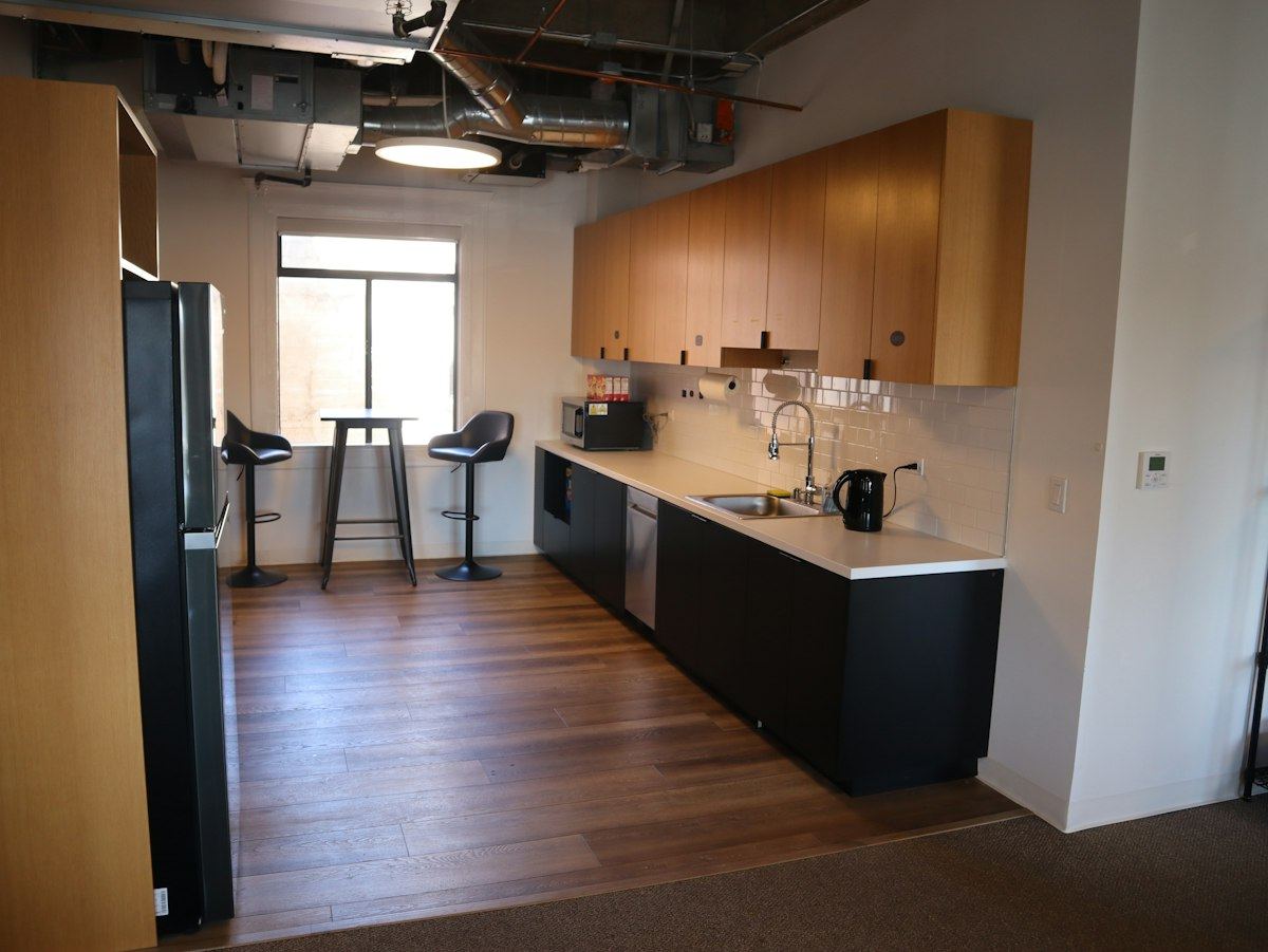 A tidy shared office kitchen with wooden cabinets and a long worktop
