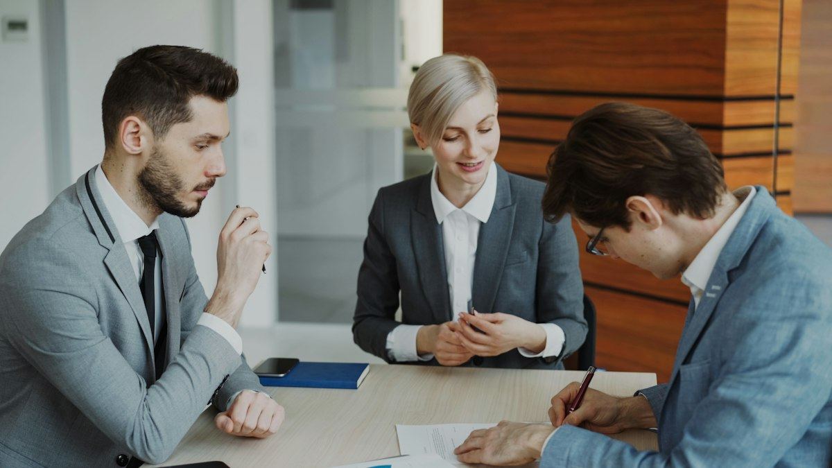 Three colleagues reviewing an agreement across a table