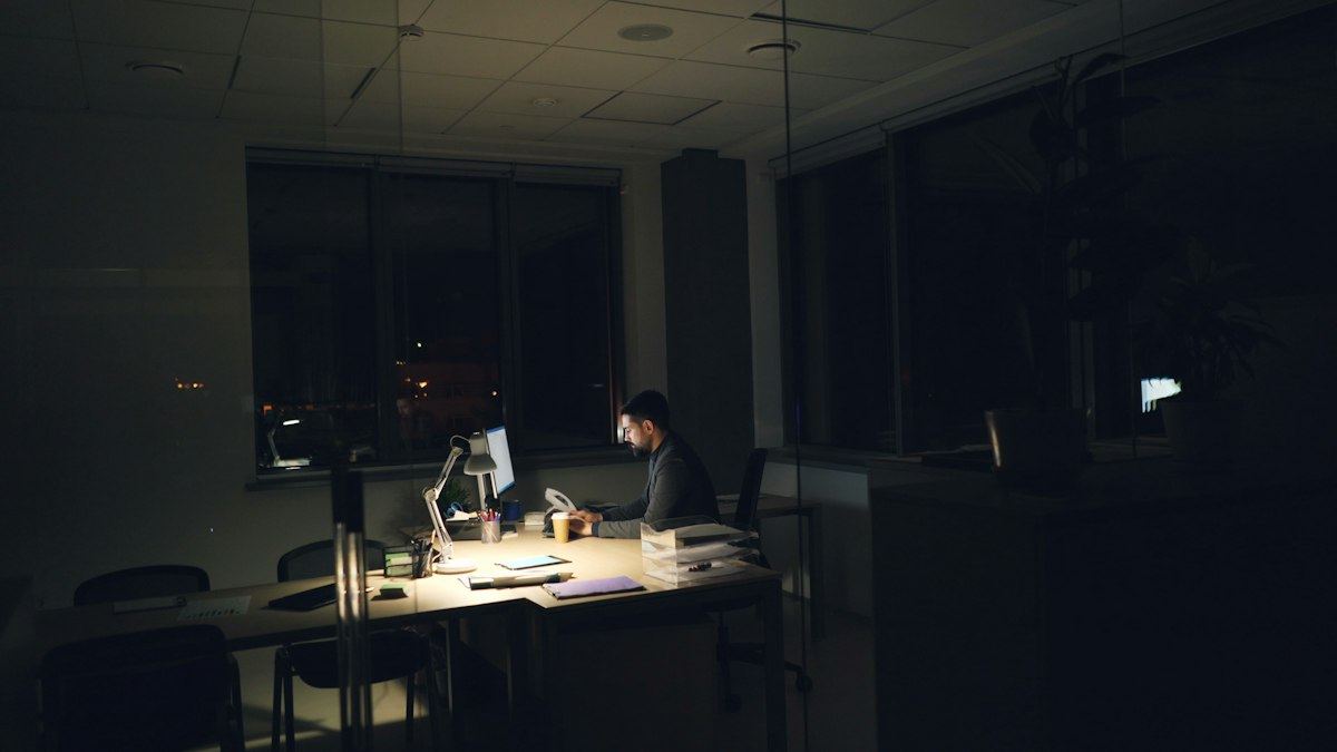 A dimly lit office at night with one person still working at a desk