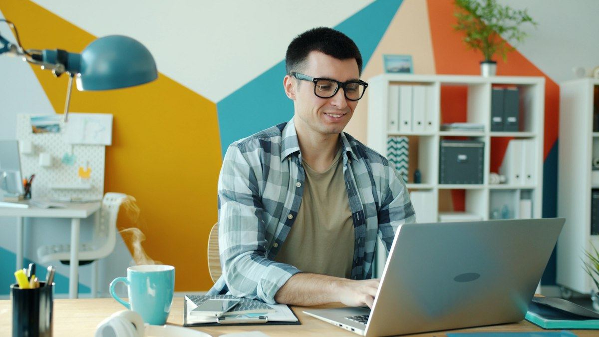 A person working on a laptop at a bright, colourful desk