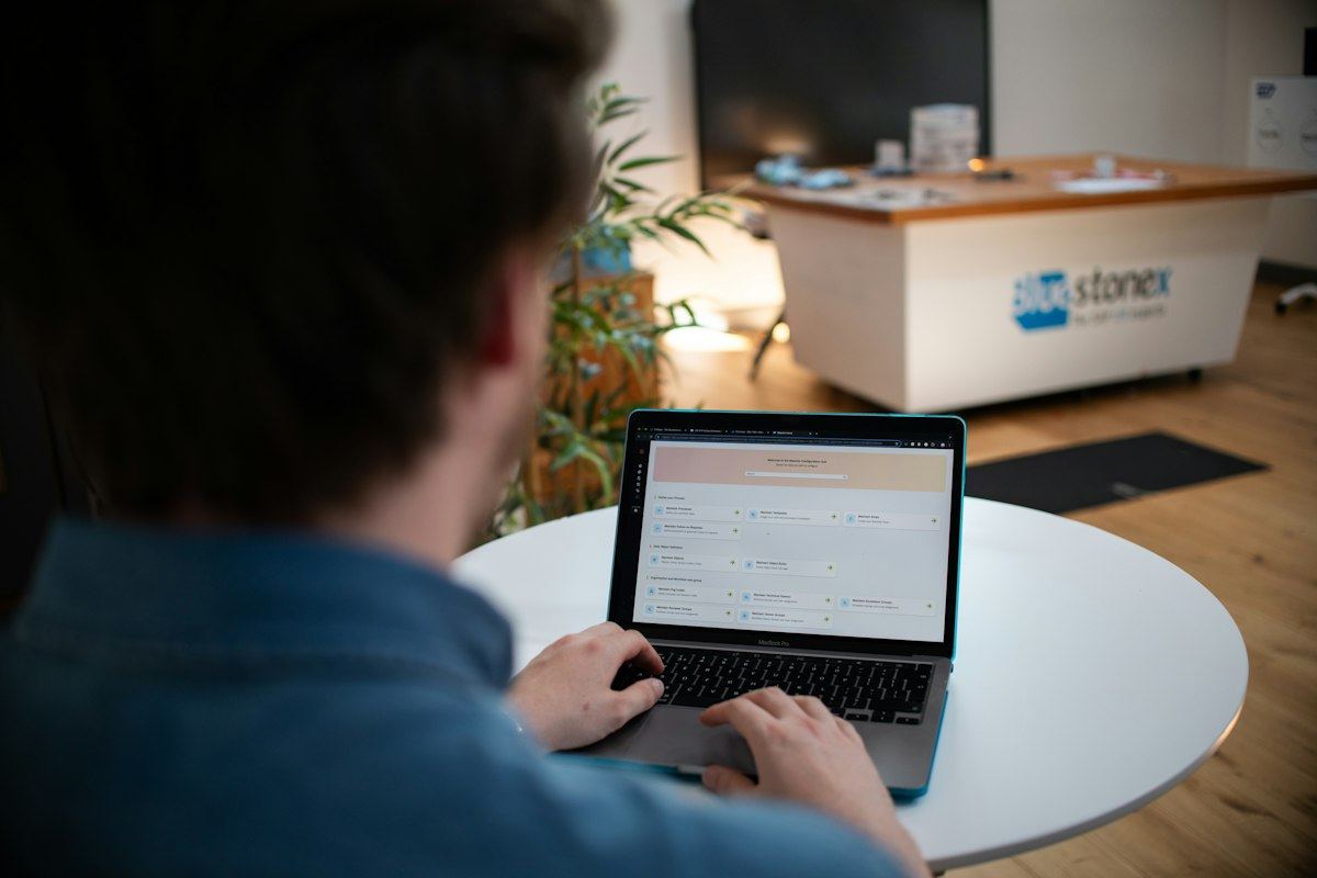 Someone working on a laptop at a shared table in an open office
