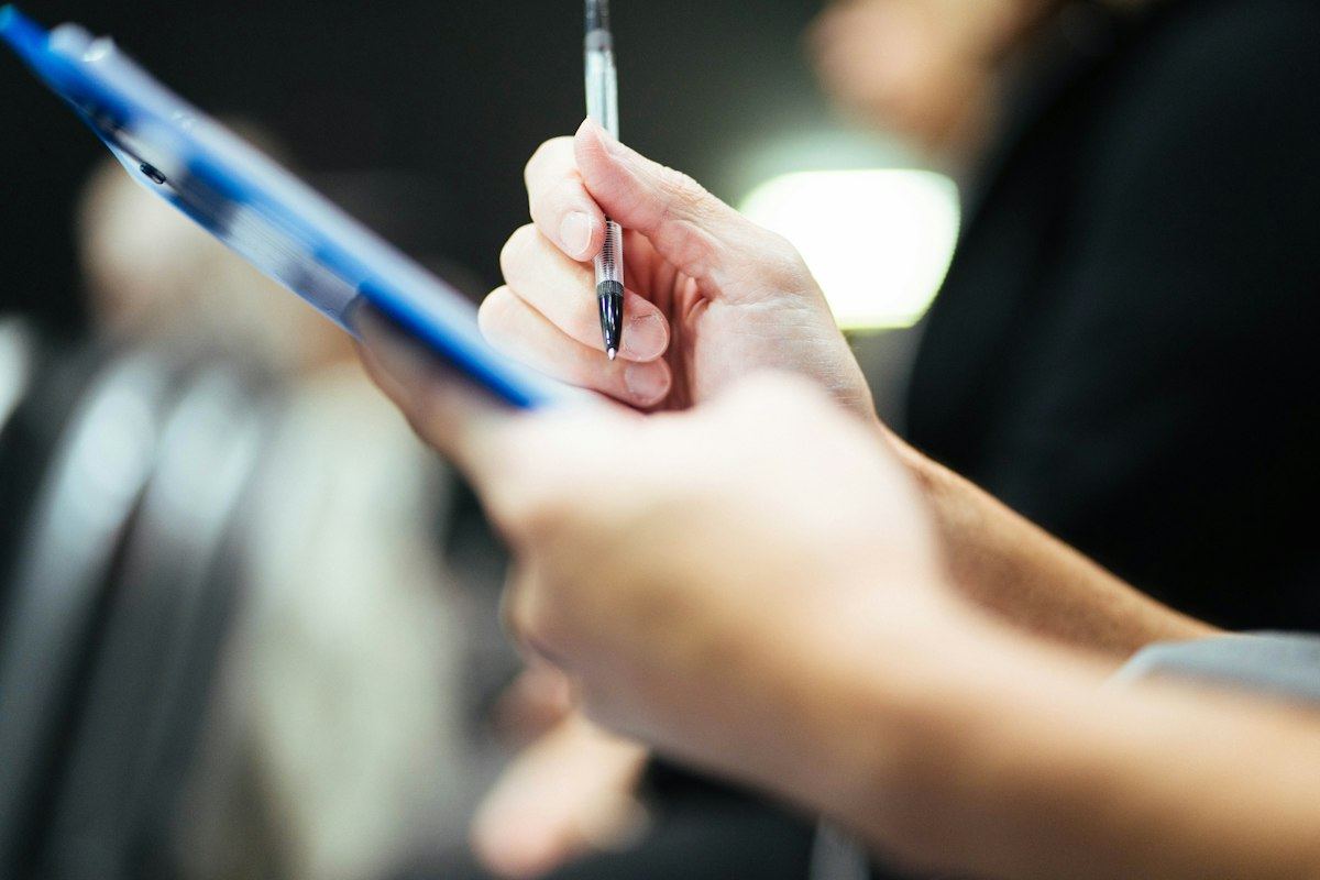 A person taking notes on a clipboard during a site visit