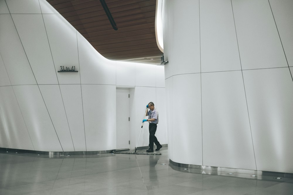 A cleaner working across a polished floor in a bright corridor