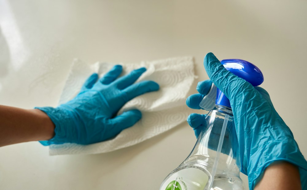 Gloved hands wiping down a clean office surface