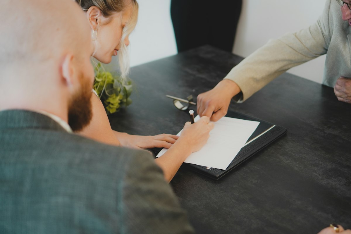 Two people signing documents at a desk in an estate agent’s office