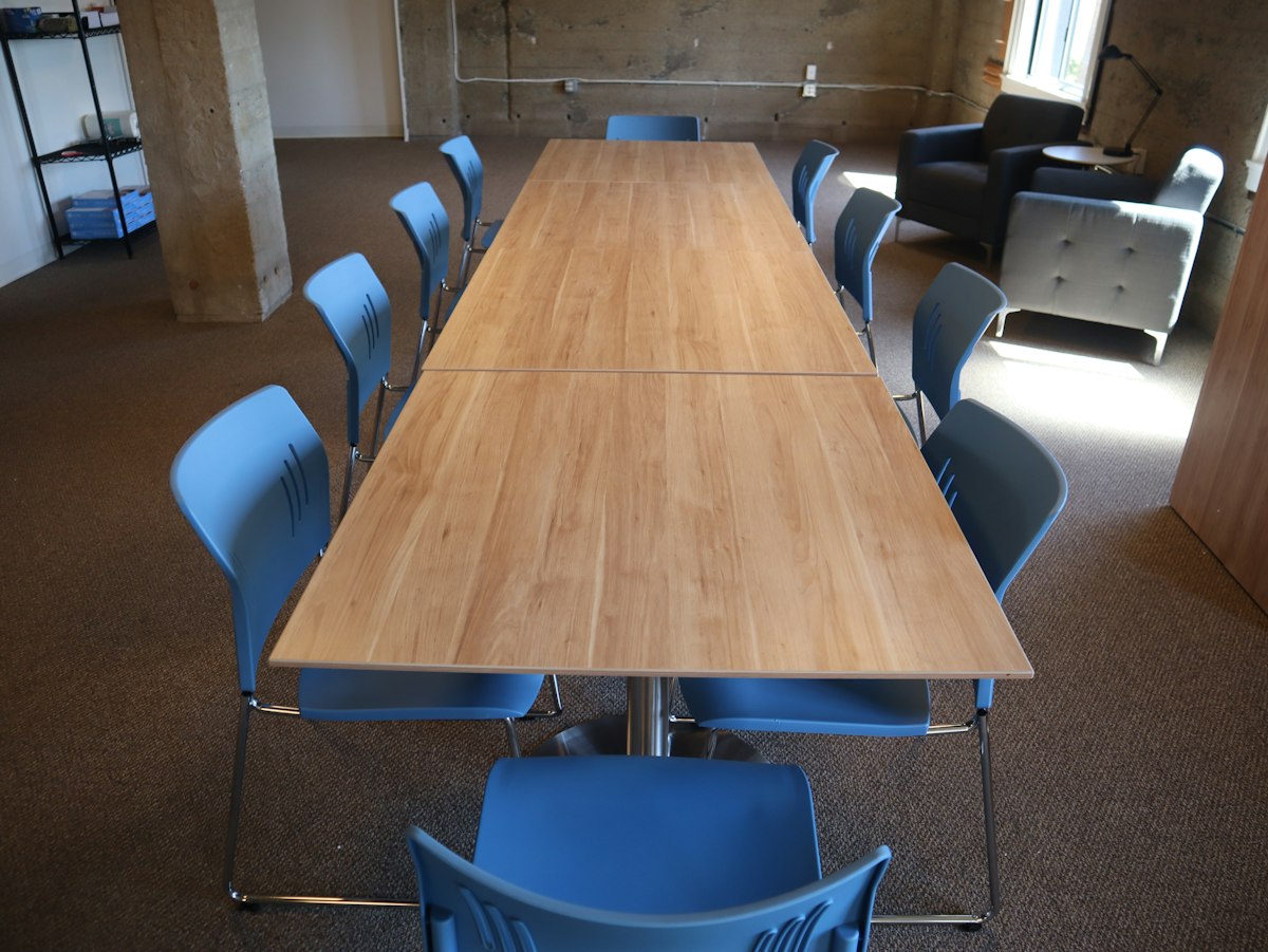 A long wooden boardroom table with blue chairs in a professional office