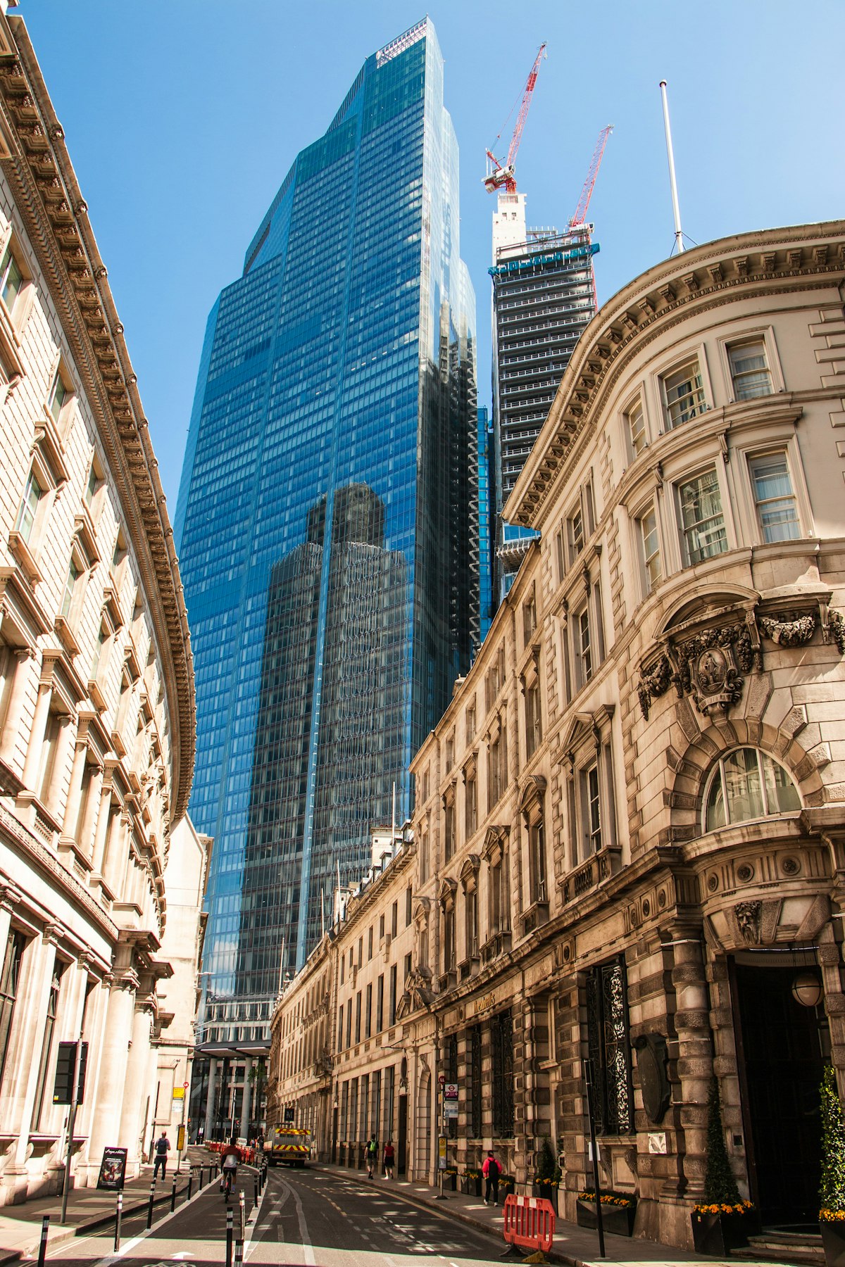A glass tower beside a Victorian stone building in the City of London