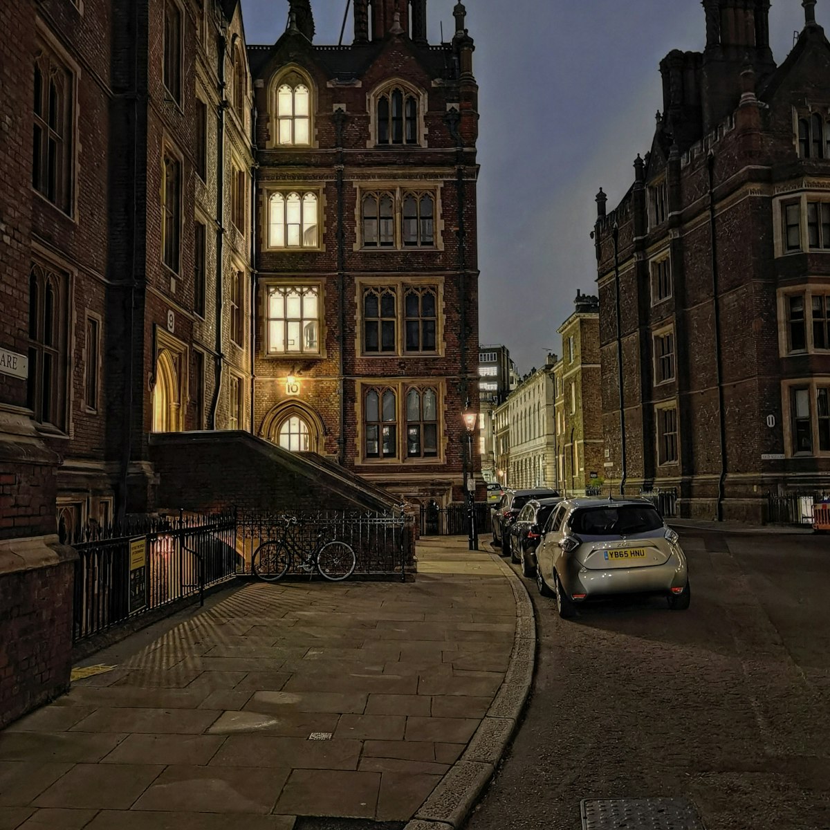 A historic brick street with Gothic buildings in central London at dusk