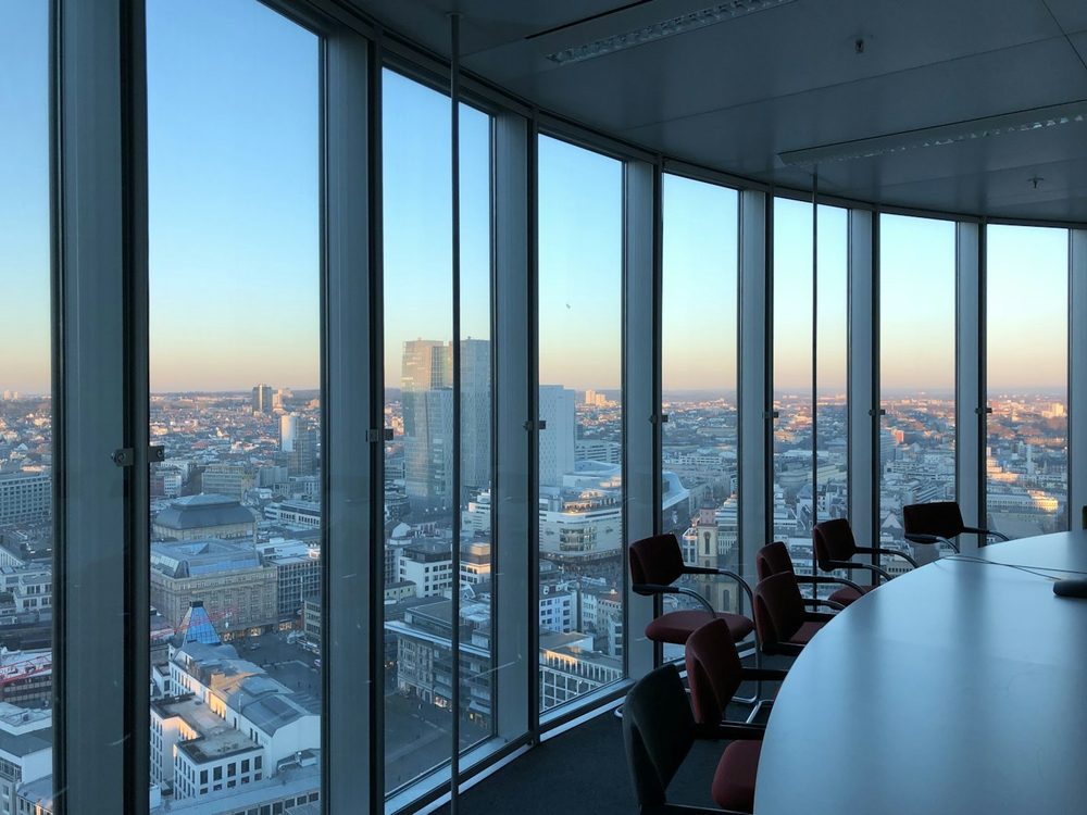 An office meeting room with curved floor-to-ceiling windows over a city skyline at dusk, the kind of Barbican office we clean