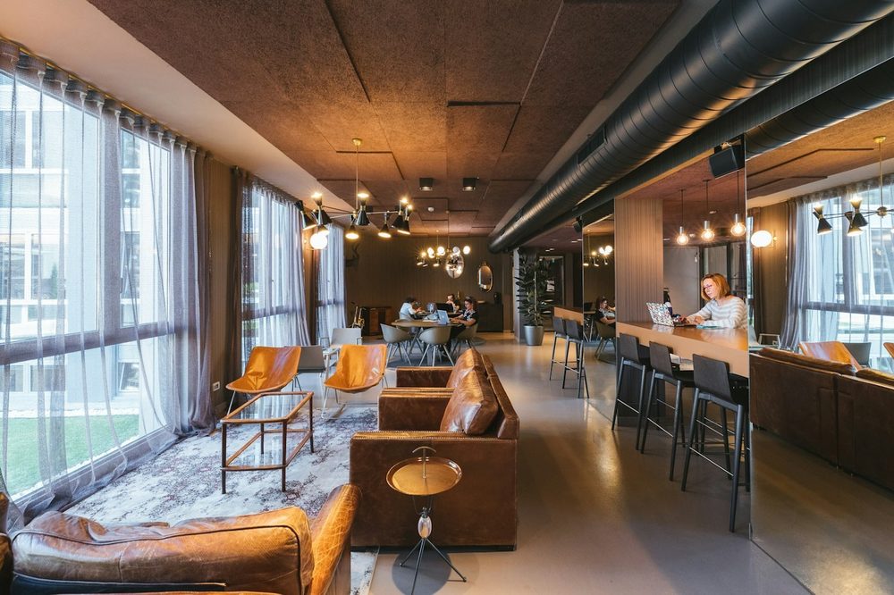 A warm industrial-style office lounge with exposed ceilings and large windows, the kind of Battersea office we clean