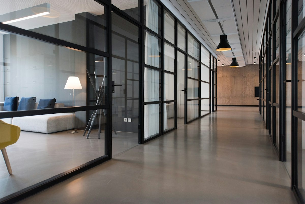 A long glass-walled office corridor with warm wood and daylight, the kind of Holborn workplace we clean