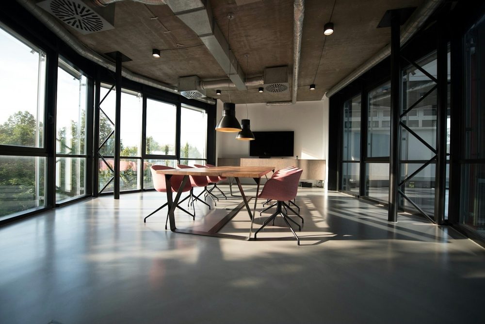 A light industrial-style office with floor-to-ceiling windows and a long meeting table, the kind of Soho office we clean