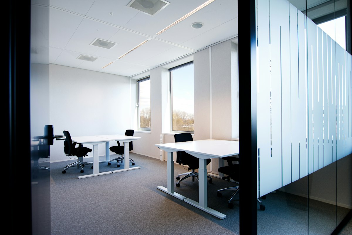 A bright office with white desks and glass partitions
