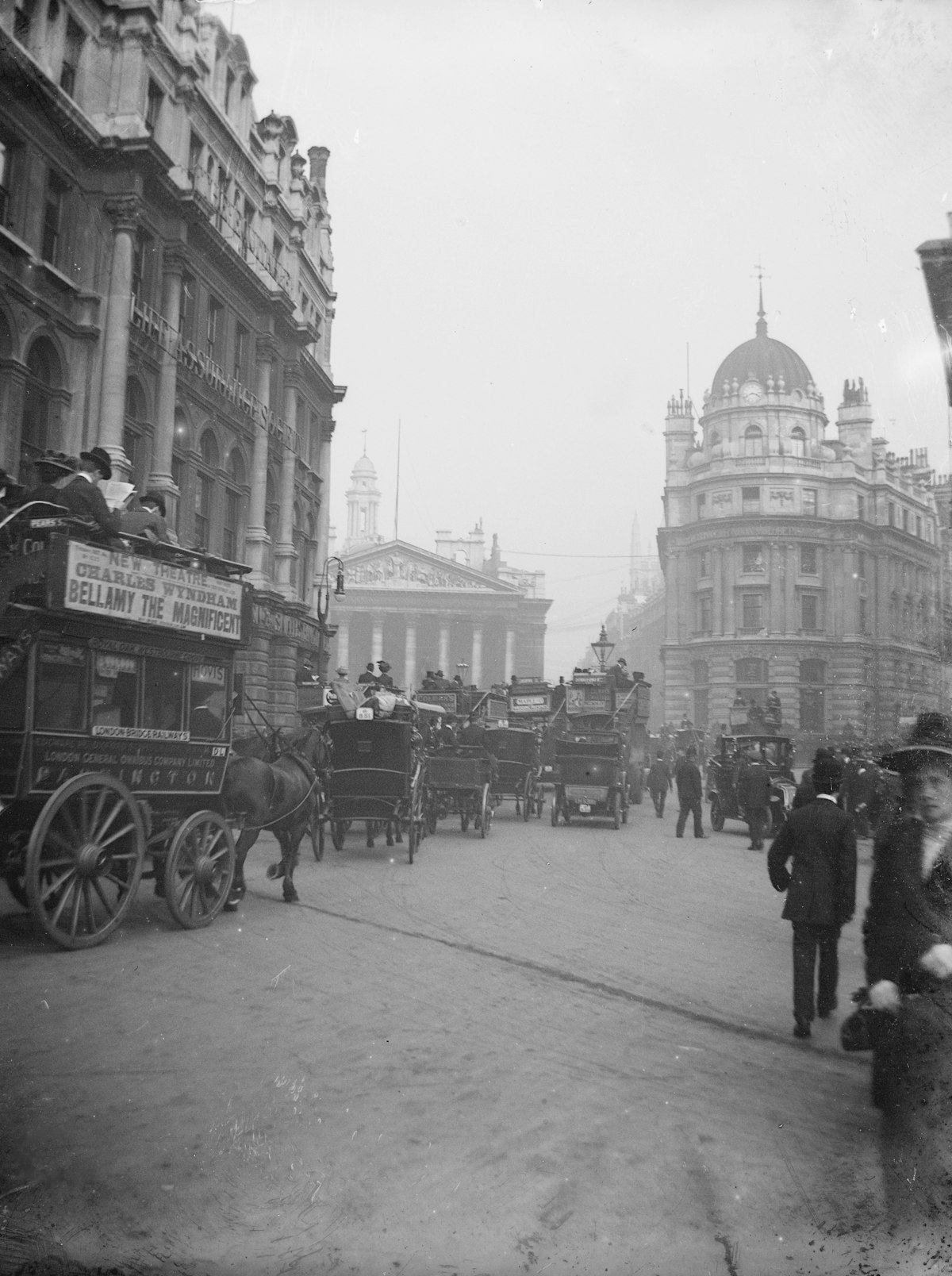 An old black and white photograph of a busy London street with horse-drawn buses