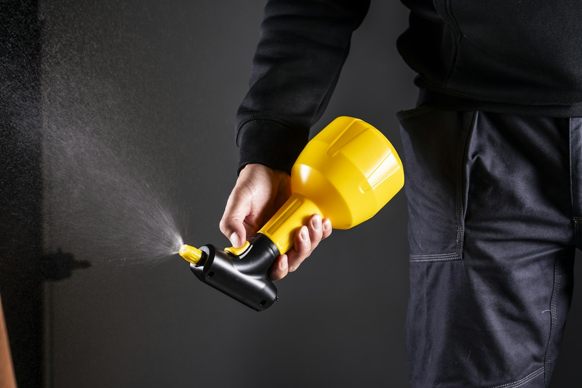 A cleaner spraying disinfectant with a hand-held sprayer during a deep sanitising visit