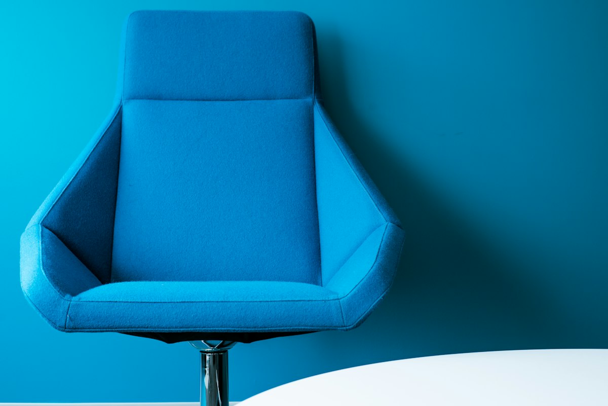 A blue upholstered office chair against a matching blue wall