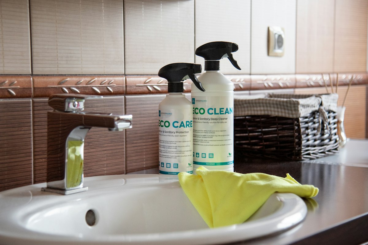 A washroom sink with eco cleaning sprays and a cloth ready for use