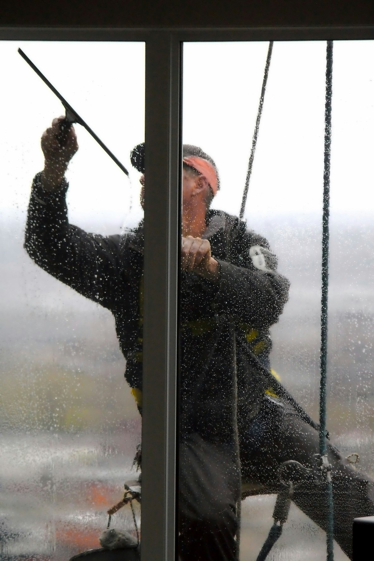 A window cleaner using a squeegee on a high pane of glass